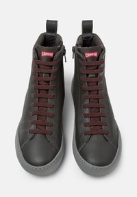 Zwarte leren high-top sneakers met bordeauxrode veters en Camper-logo, weergegeven in een frontzicht met een grijze rubberen zool.
