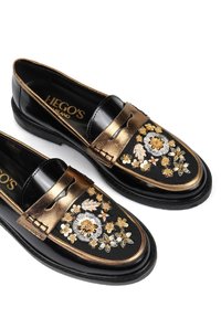 Czarne skórzane mokasyny z metalicznie złotymi akcentami i haftem kwiatowym. Posiadają okrągły czubek oraz wsuwany fason z dekoracyjnym przeszyciem.