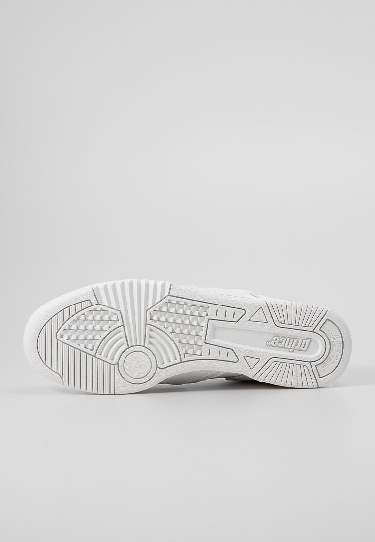 Suela de zapatilla blanca con patrones texturizados, ranuras y el nombre de la marca "Prince" visible en la zona del talón, sobre un fondo claro y liso.