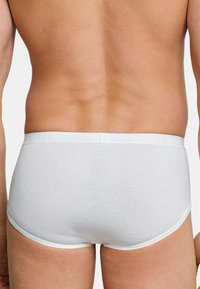 Witte katoenen slips met een lage taille. Voorzien van een elastische tailleband met een ingebrande merknaam en platte naden voor comfort.