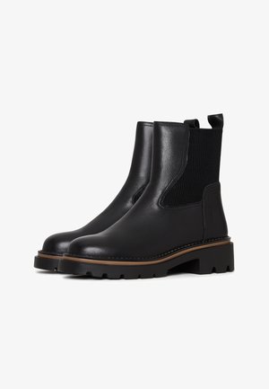 Bottines en cuir noir avec des panneaux latéraux élastiques, bout rond et semelle en caoutchouc épaisse avec un bord brun contrastant.