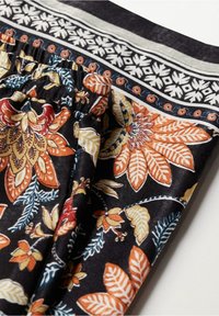 Tissu noir avec des motifs floraux et de feuilles orange, jaune et crème, doté d'une ceinture élastique et d'une bordure décorative.