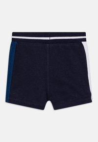 Marina badshorts med vita och blå sidopaneler. Tillverkat av mjukt tyg, med en bekväm elastisk midjeband som har en vit rand.