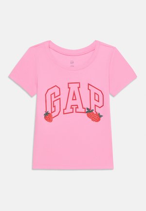 Ružičasta majica s kratkim rukavima s crvenim slovima GAP i tri crvene jagode ispisane sprijeda.
