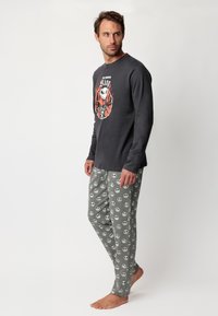 Camisa de algodón gris de manga larga con estampado de Jack Skellington, combinada con pantalones de pijama grises que tienen un patrón de calaveras repetido.