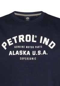Marineblauwe sweatshirt met een ronde hals en lichtgrijze accenten. Voorzien van vetgedrukte witte tekst: "PETROL IND," "ALASKA U.S.A.," en "SUPersonic."