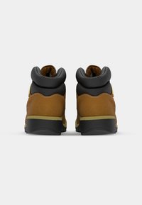 Brown leather hiking boots with a black padded collar, rubber soles, and yellow accents, featuring a textured finish and durable design.