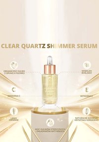 Sérum scintillant en cristal de quartz clair dans un flacon compte-gouttes en verre transparent avec un bouchon en or rose. Contient un fluide doré scintillant et des étiquettes textuelles.