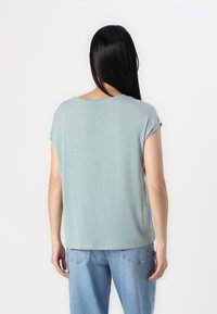 Lyseblå kortærmet top med en afslappet pasform og rund halsudskæring, parret med lyse denimjeans. Glat stof og afslappet design.