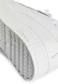 Zapatilla blanca con suela de goma texturizada y agarre estampado, parte superior de cuero suave y detalles de costura sutiles.