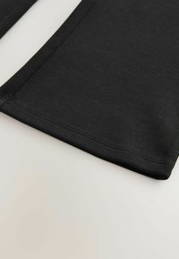 Svart bomulls tyg med en slät textur och rena kanter, med en enkel, odekorerad design och välgjorda sömmar.