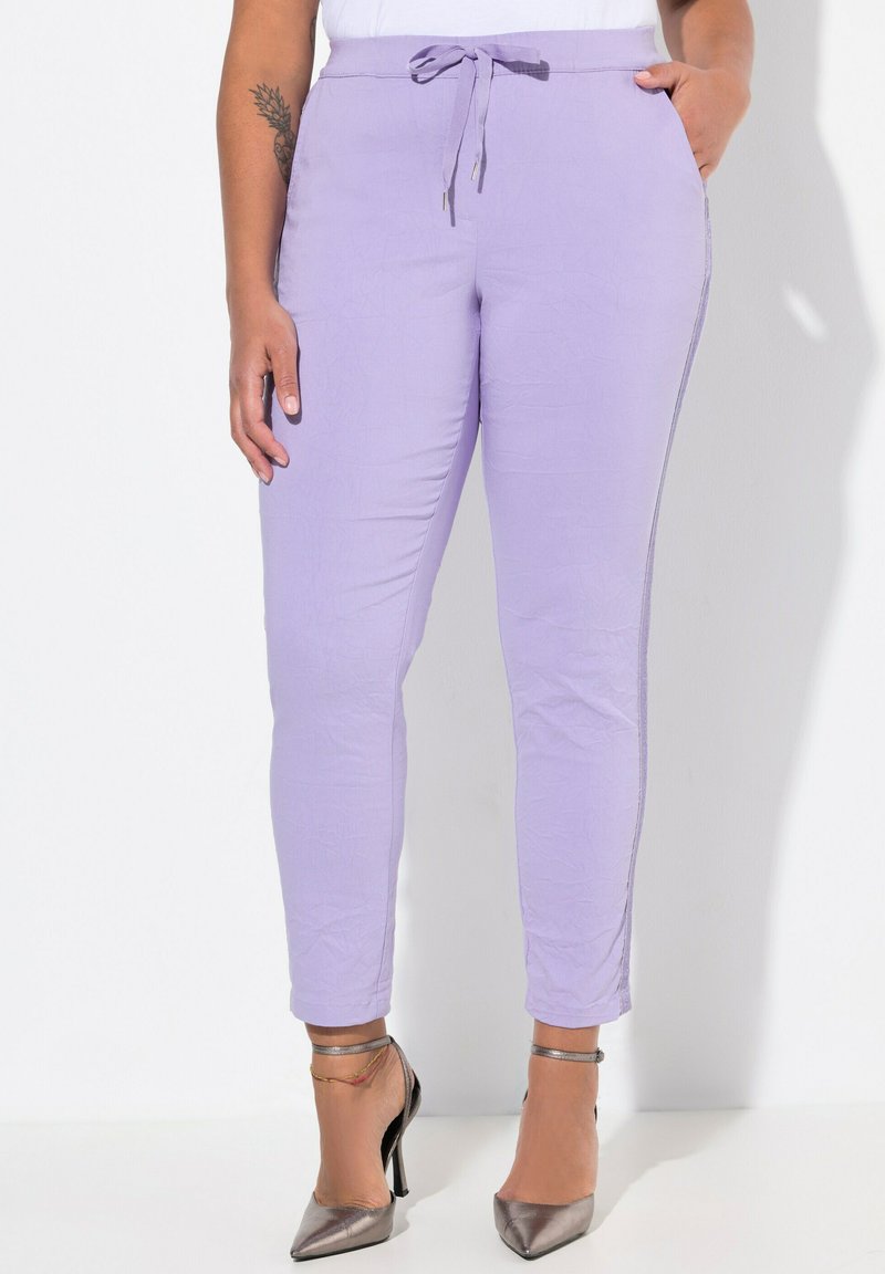 Ljust lila byxor i ett strukturerat tyg, med dragsko i midjan och sidofickor, kombinerat med silvriga högklackade skor.