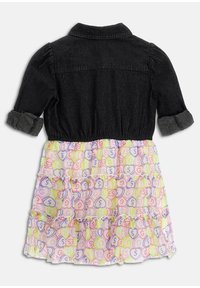 Svart denimtop med krage och uppvikt ärm, lager på lager med en färgglad, volangkjol med upprepade pastellfärger på en ljus bakgrund.