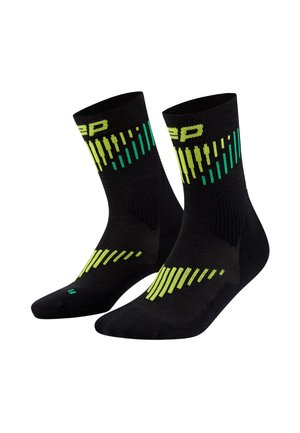 Chaussettes de sport noires avec des motifs de rayures verticales vertes et jaunes, talon et orteil renforcés, et un tissu texturé pour un meilleur maintien.
