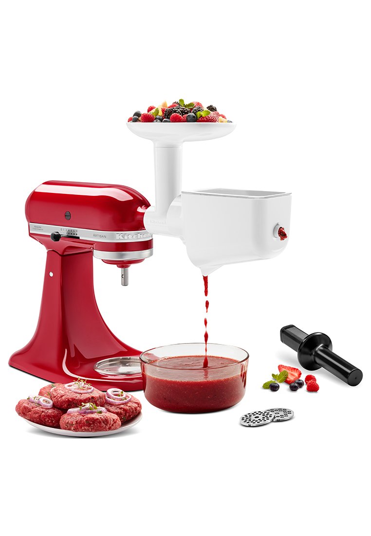 Batidora KitchenAid roja con accesorio blanco para procesador de alimentos, bol de vidrio que recoge puré rojo, empujador negro y plato de hamburguesas crudas con hierbas.