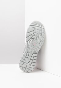 Semelle en caoutchouc blanc avec un profil texturé, comportant un logo et une indication de taille. Le design inclut des motifs de grip pour plus d'adhérence.