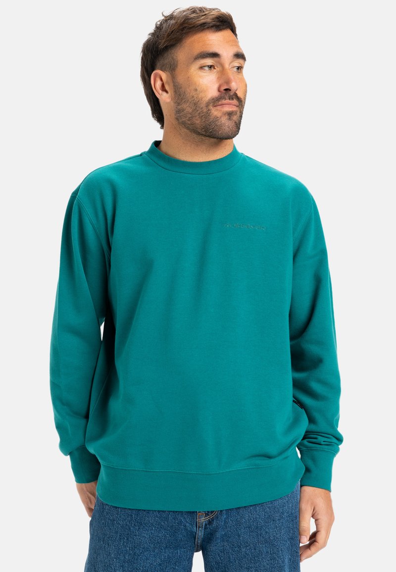 Teal sweatshirt lavet af blødt stof, med rund hals, lange ærmer og en afslappet pasform. Logo præget på brystet.