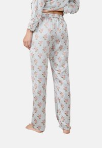 Floral-gepatroonde pyjamabroek met een elastische tailleband. Heeft afwisselende strepen en kleine roze bloemen tegen een witte achtergrond.