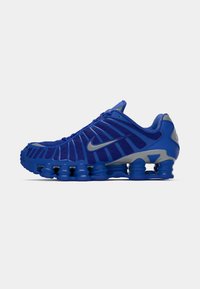Chaussure de course Nike bleue avec une tige en maille, un design nervuré et une semelle intérieure unique avec des éléments cylindriques proéminents.