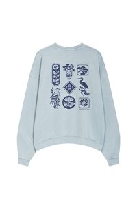 Light blue oversized sweatshirt featuring dark blue graphic prints of flowers, birds, and geometric shapes; rounded hem and relaxed fit.