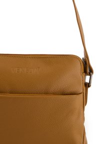 Brown leather crossbody bag with textured finish, featuring a top zipper and front pocket, and an adjustable shoulder strap.