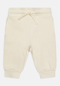 Pantalons de survêtement couleur crème en tissu doux, avec une taille élastique et un cordon de serrage, deux poches latérales et des poignets côtelés.