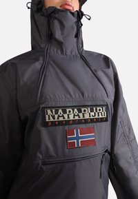 Grå vandtæt jakke med høj krave, prydet med et fremtrædende logo-patch og detaljer med Norges flag. Design med lynlås-lommer inkluderet.