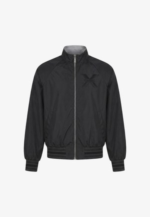 Giacca bomber nera con cerniera, polsini e orlo a costine, collo alto, tasche laterali e un sottile logo "X" sul petto sinistro.