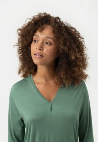 Groene V-hals shirt van zachte stof, met lange mouwen en een subtiele plooidetail bij de halslijn. Glad textuur met een casual pasvorm.