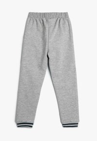 Pantalones de chándal grises con cinturilla elástica y puños acanalados, con rayas azules y blancas en el tobillo. Tejido suave y texturizado.
