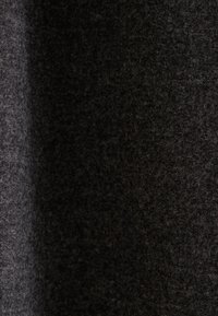 Gros plan sur un tissu en laine gris foncé et noir montrant des fibres douces, texturées et denses avec un léger dégradé de gauche à droite.