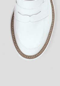 Białe skórzane buty z okrągłym czubkiem, z ozdobnym paskiem i przeszyciem wzdłuż podeszwy, która ma jasnobrązowe wykończenie.