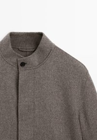 Gray wool coat with a high collar, single black button closure, and smooth texture. Features clean lines and minimalistic design.