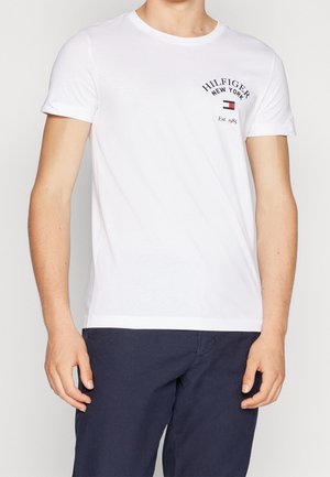T-shirt bianca a maniche corte in cotone, con colletto rotondo e stampa logo sul petto in colori blu navy e rosso.