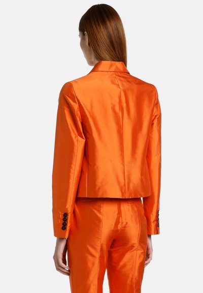 Oranžna satenska blazer jakna s skrajšanim dizajnom, dolgimi rokavi in gumbi na manšetah, v kombinaciji z ujemajočimi hlačami.