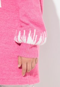 Helle pinke Sweater mit gerippten Bündchen. Die Bündchen sind mit weißen Pinselstrichmustern versehen. Weiche Textur, die einen lockeren Schnitt und einen lässigen Stil präsentiert.