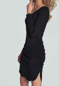 Schwarzes Langarmkleid mit seitlichen Raffungen, taillierter Silhouette und einem Saum mit einem subtilen Schlitz. Hergestellt aus weichem, dehnbarem Material.