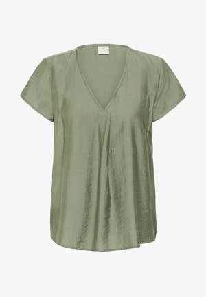 Trumpa rankovėmis viršūnė iš minkštos, šviesiai žalios medžiagos su V formos iškirpte ir raukiniais priekyje. Lygus tekstūra, šiek tiek laisva forma ir asimetriška apačia.