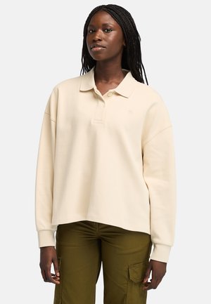 Cremefarvet oversized polo sweatshirt med klassisk krave, kort knaplukning og ribbede manchetter, parret med olivenfarvede cargo bukser.