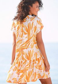Kurzärmliges Kleid aus weißem Stoff mit lebhaften orange und gelb abstrakten Blattmustern; verfügt über einen gestuften Rüschensaum für eine fließende Silhouette.