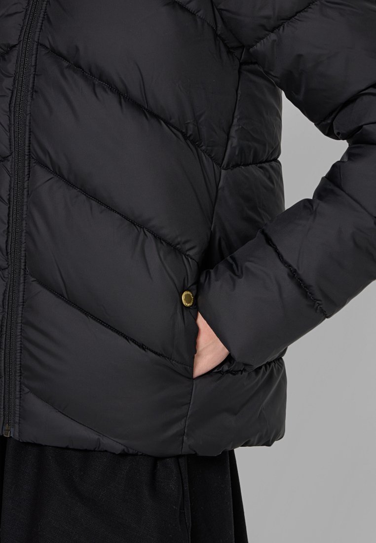 Schwarze Pufferjacke mit gestepptem Design, ausgestattet mit einem Frontreißverschluss und einem goldenen Druckknopfdetail an der Tasche. Glatte Textur.