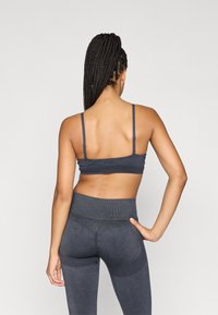 Ανθρακί αθλητικό σουτιέν με ρυθμιζόμενους ιμάντες και υφασμάτινους κολάν ψηλής μέσης, με ραφές και απρόσκοπτο σχεδιασμό.