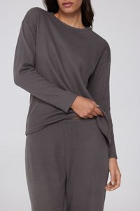 Šedý žebrovaný top s dlouhým rukávem a lodičkovým výstřihem. Měkká tkanina; volný střih s jemnými bočními rozparky. Spárováno s odpovídajícími šedými kalhotami.