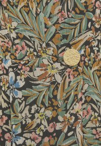 Blommig tyg med gröna, beige och rosa blommor mot en svart bakgrund, texturerad yta med en guldfärgad, cirkulär knappdetalj.