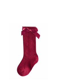 Rote gerippte Strickbaby-Socke mit einer glänzenden Satinschleife, die am Bund gebunden ist, auf einem weißen Hintergrund präsentiert.