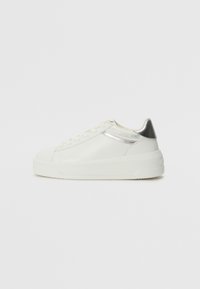 Sneaker bianca in pelle con un accento argento sul tallone e una striscia lucida. Presenta una suola piatta e chiusura con lacci. La superficie testurizzata aggiunge dettaglio.