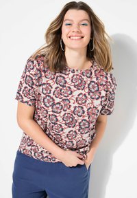 Kurzarmoberteil mit einem cremefarbenen Grund und einem Blumenmuster in Rot und Marineblau. Der Stoff ist glatt und hat eine lässige Passform.