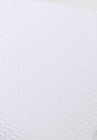 Biely texturovaný materiál so vzorom v cik-cak, s jemným, nadýchaným povrchom. Dizajn vytvára jemnú hĺbku a vizuálny záujem.