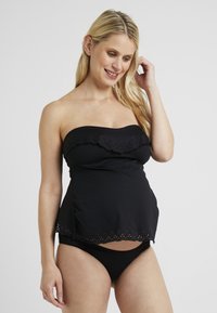 Costume da bagno nero a bandeau con bordo scallopato e dettagli perforati. Slip abbinato nero. Texture liscia, design aderente.