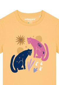 Gele t-shirt met daarop twee gestileerde katten: een marineblauwe en een roze, omringd door abstracte vormen en sterren in verschillende kleuren.